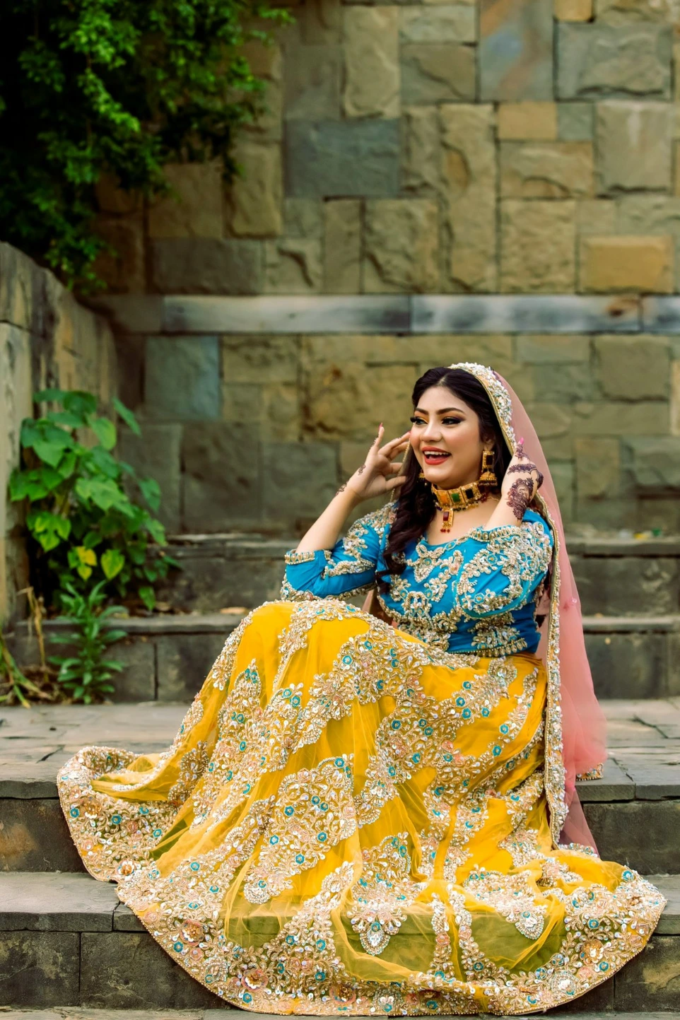 A woman in a colorful traditional outfit sits on stairs.